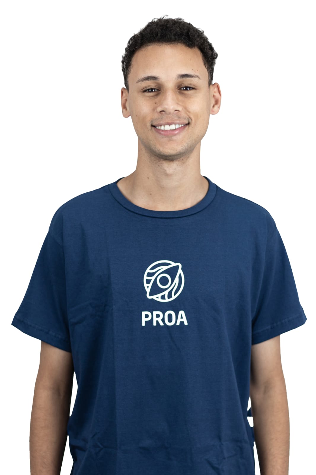 In the image, there is a young man wearing a t-shirt with the word PROA printed on it. The t-shirt is blue, and it has an eye logo on it. The man is looking up at the camera and smiling. He has curly hair, and he recently had a hair transplant. The image also includes a close-up of the man's nose.