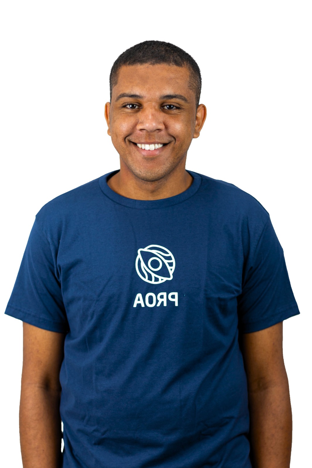 A imagem apresenta um homem usando uma camiseta com o logotipo da marca de moda Proa. O logotipo está proeminentemente exibido na parte da frente da camiseta. O homem está sorrindo e é o foco central da imagem. O logotipo da Proa está em letras em negrito, e o homem parece confiante e descontraído.A imagem também inclui um close-up do rosto do homem, permitindo uma visão clara de suas características. Ele tem uma expressão amigável e está sorrindo, o que aumenta ainda mais a impressão positiva geral da imagem. No geral, a imagem mostra um homem confiante vestindo uma camiseta da Prada e expressando uma atitude agradável.
